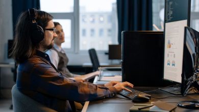 Dois programadores trabalham juntos em computadores em um escritório de tecnologia.
