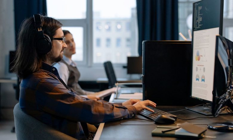 Dois programadores trabalham juntos em computadores em um escritório de tecnologia.