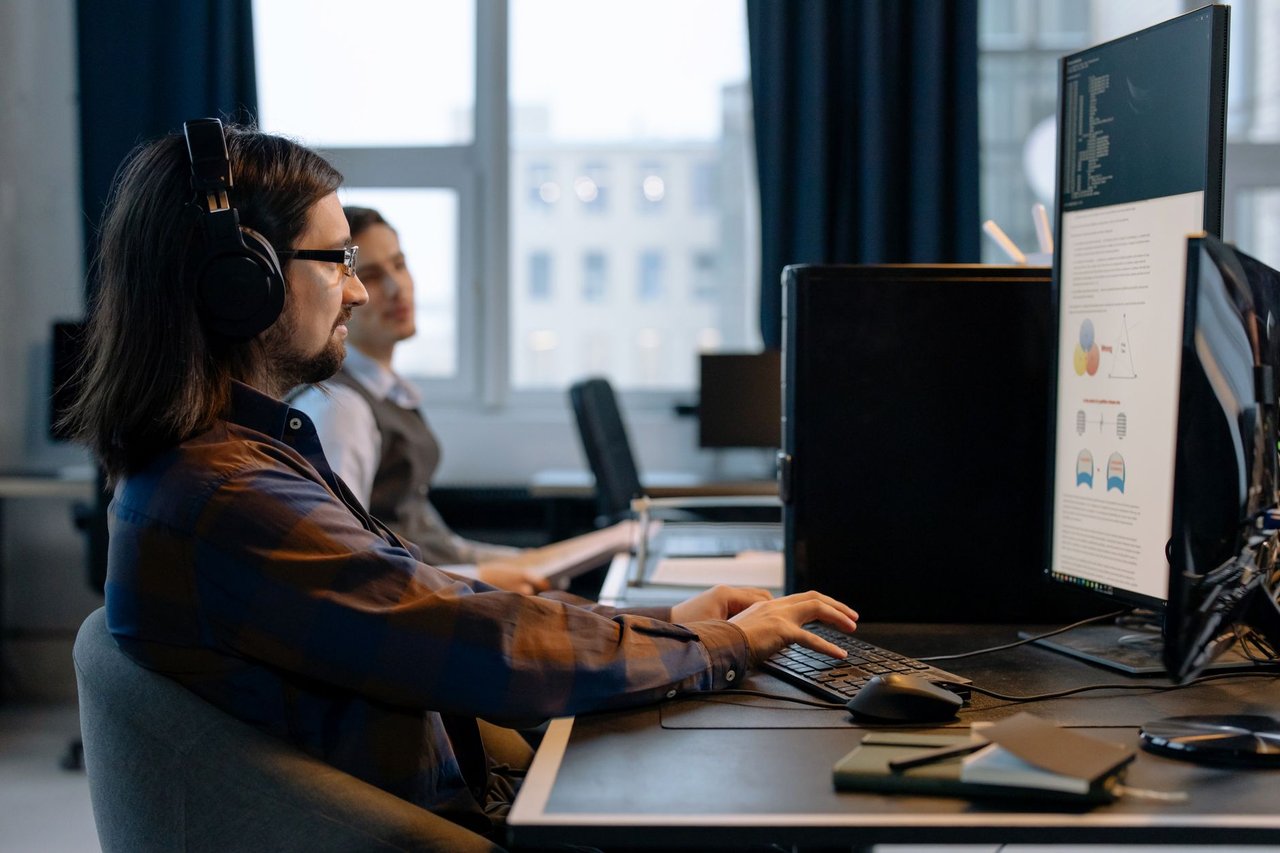 Dois programadores trabalham juntos em computadores em um escritório de tecnologia.
