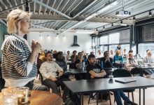 Palestrante apresenta conteúdo a um público diverso durante um workshop em ambiente moderno.