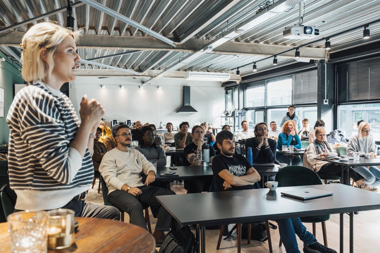 Palestrante apresenta conteúdo a um público diverso durante um workshop em ambiente moderno.