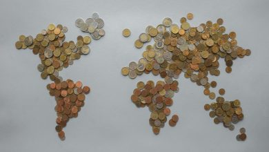 Mapa-múndi formado por moedas sobre fundo cinza, simbolizando transações e finanças globais